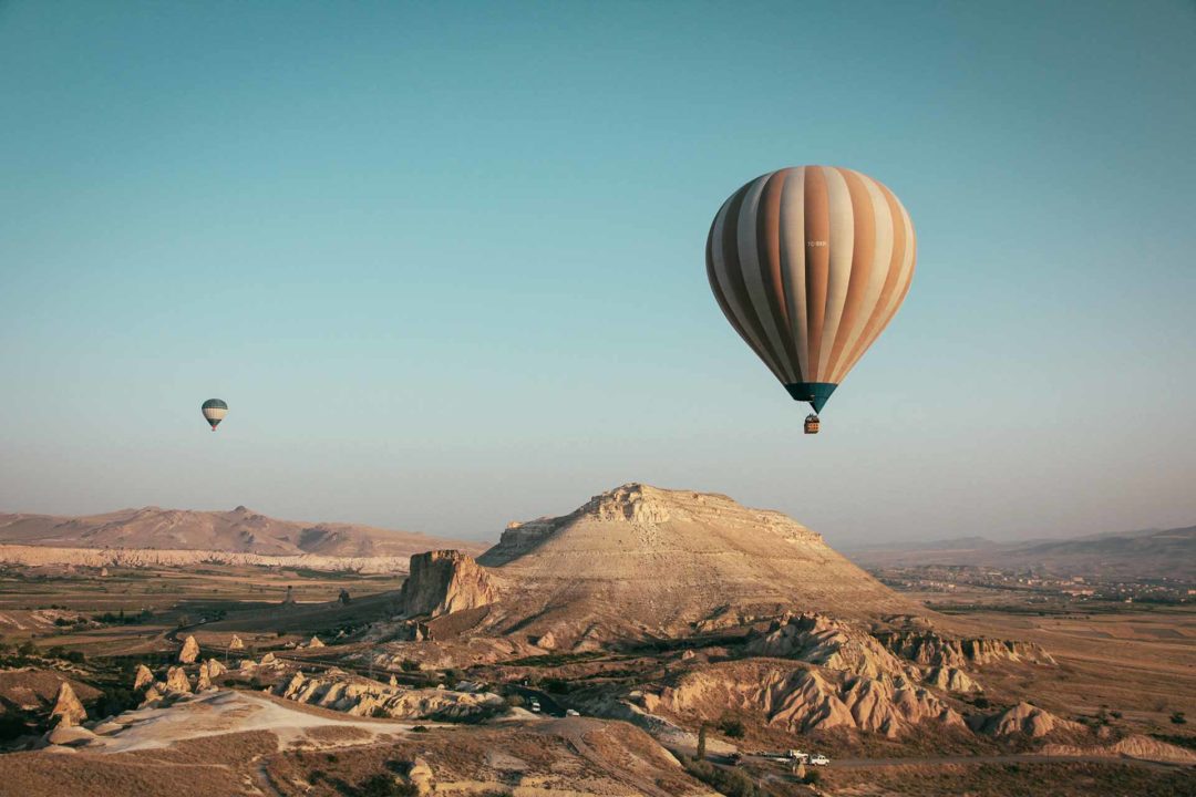Dois balões sobrevoando uma área desértica e montanhosa