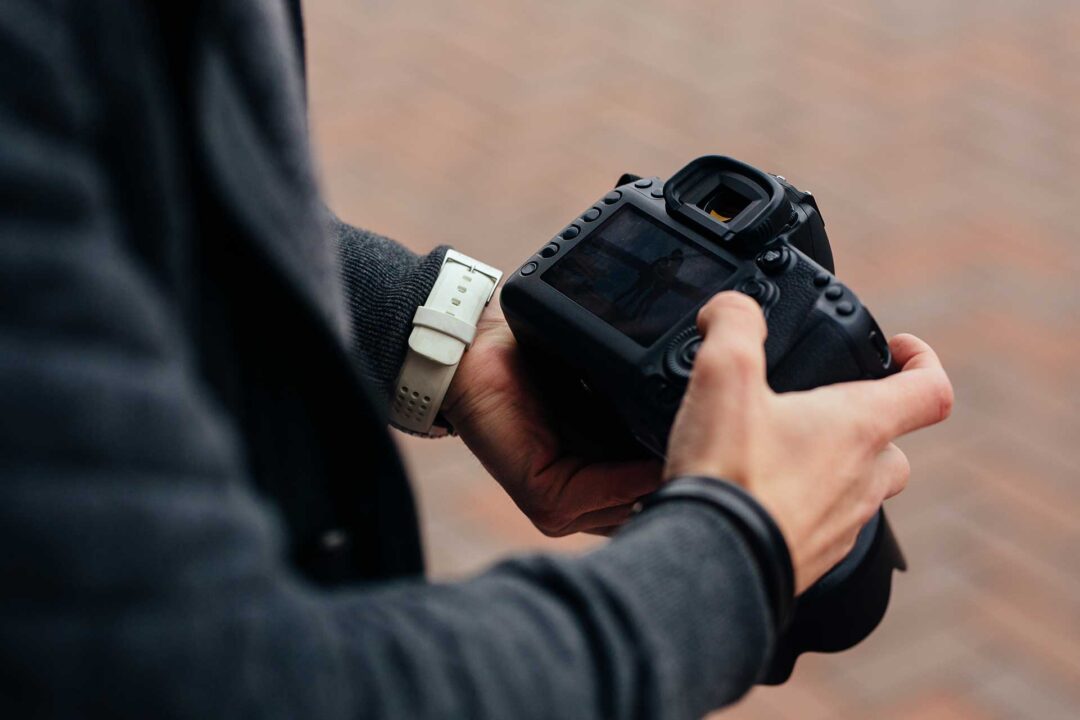 Mãos masculinas segurando uma câmera DSLR