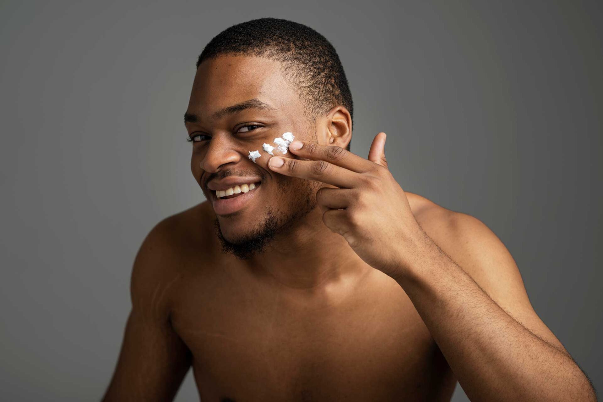 Homem de pele negra utilizando produtos masculinos no rosto