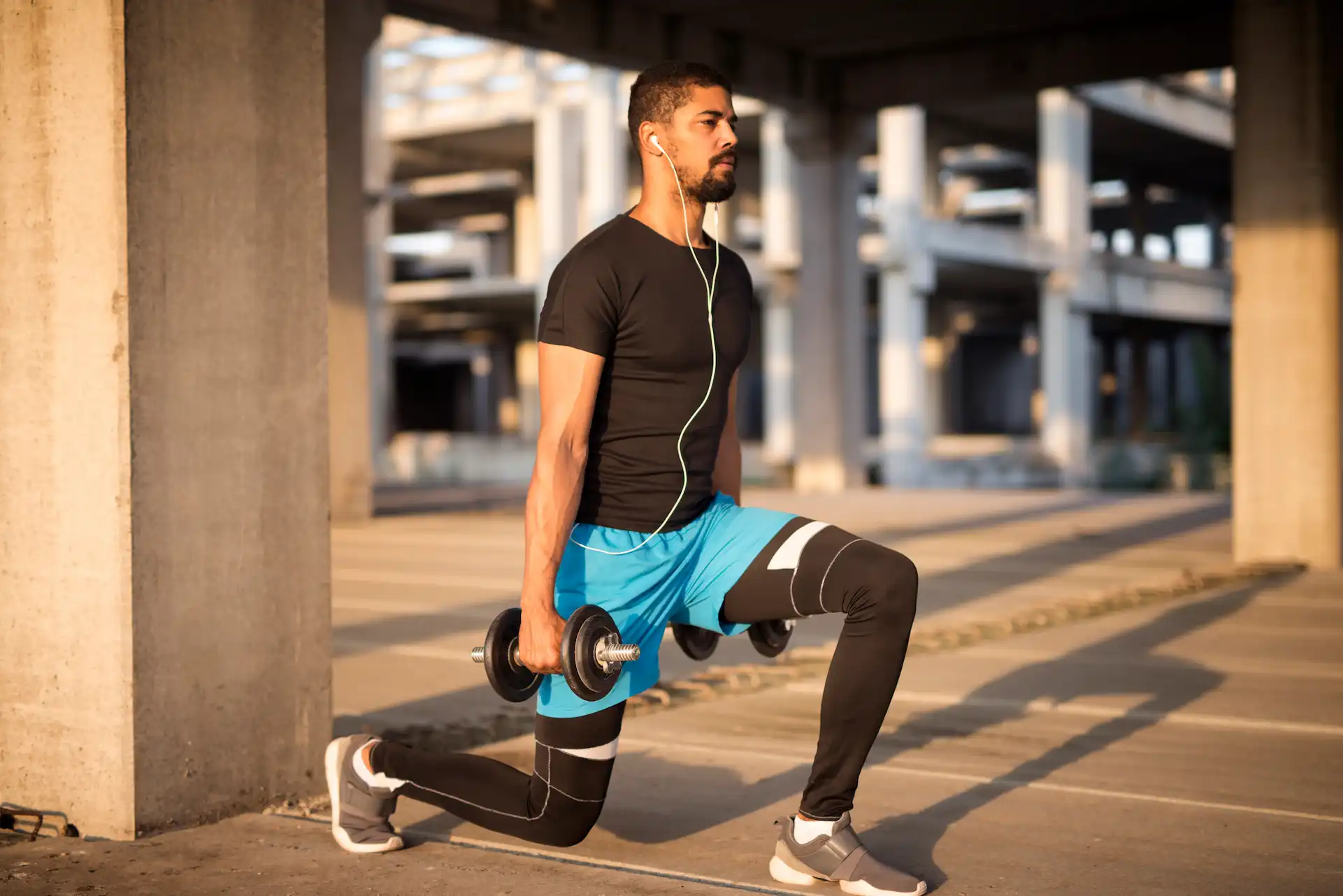 Homem segurando halteres fazendo o movimento de lunge