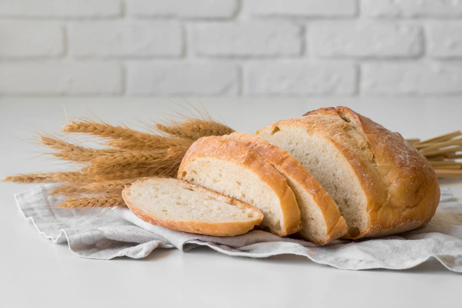 Pão artesanal parcialmente fatiado sobre uma mesa branca