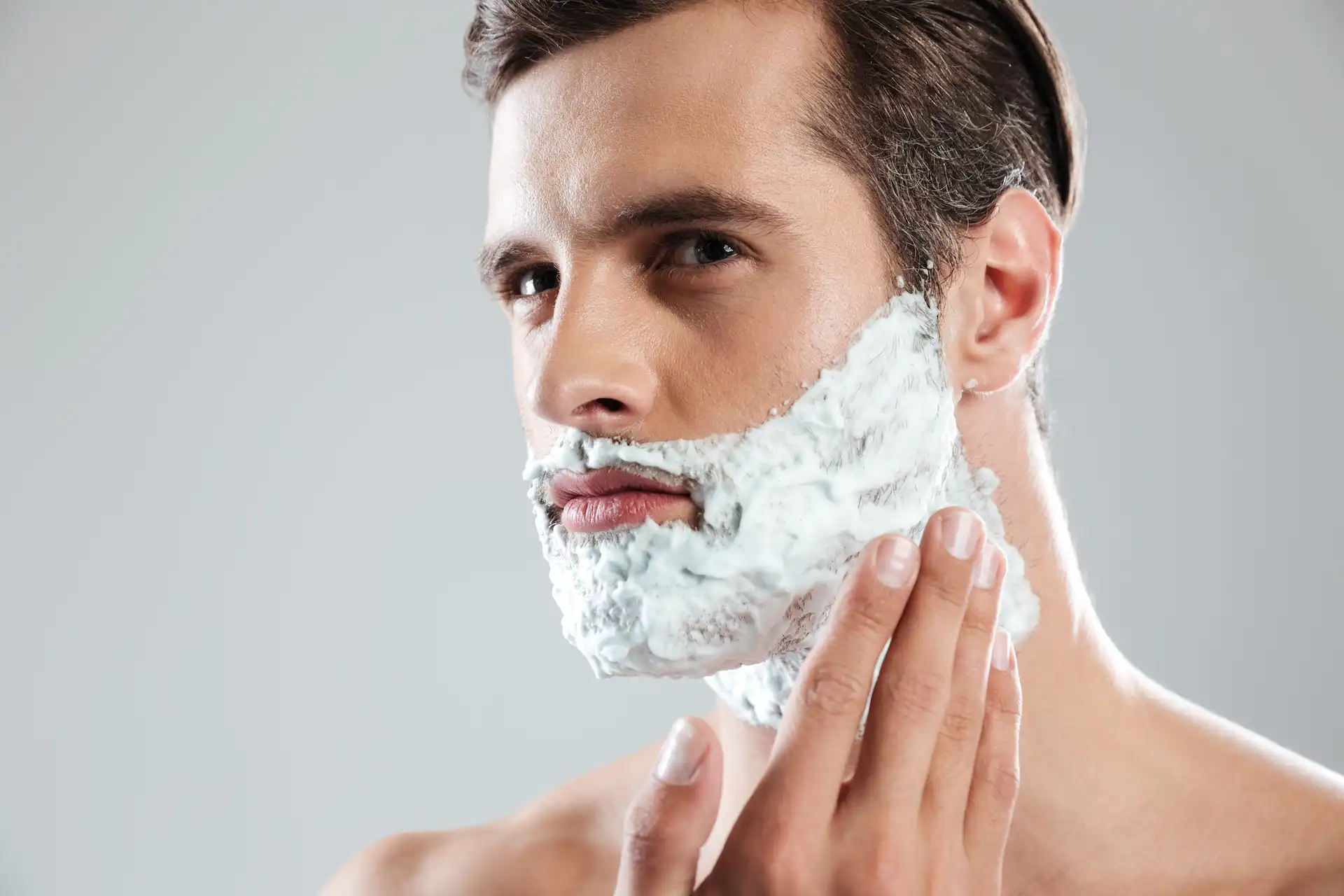 Homem utilizando espuma de barbear. Essa é uma etapa importante de como fazer a barba corretamente.