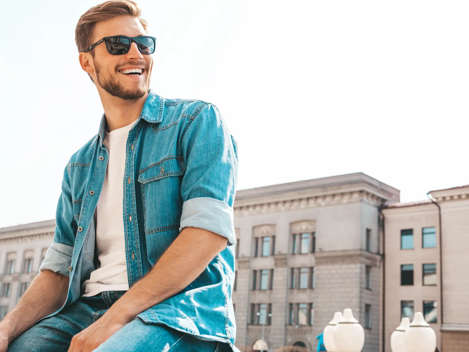 Homem usando camiseta branca, calça e jaqueta jeans e óculos escuros