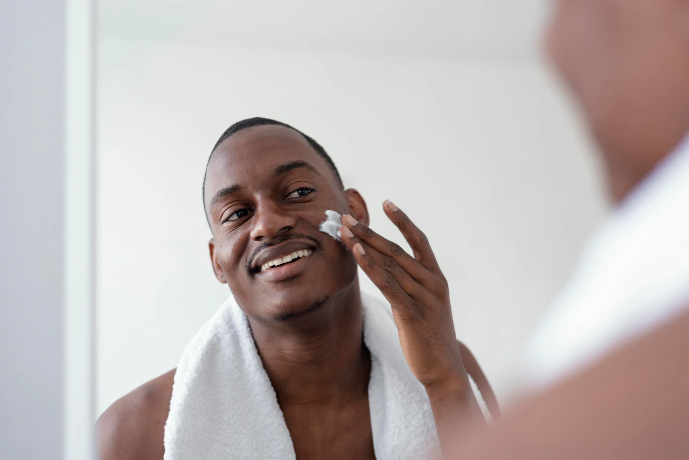 Homem se olhando no espelho enquanto faz skincare.