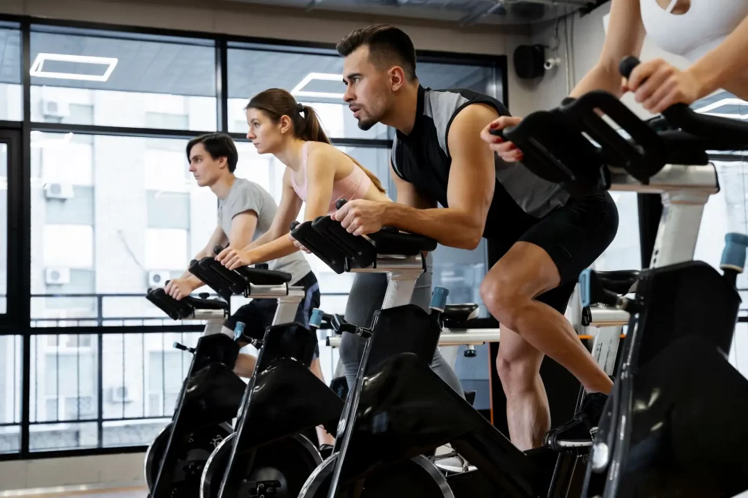 Pessoas se exercitando em bicicletas ergométricas em uma academia. Um dos vários exemplos de exercícios cardiovasculares.