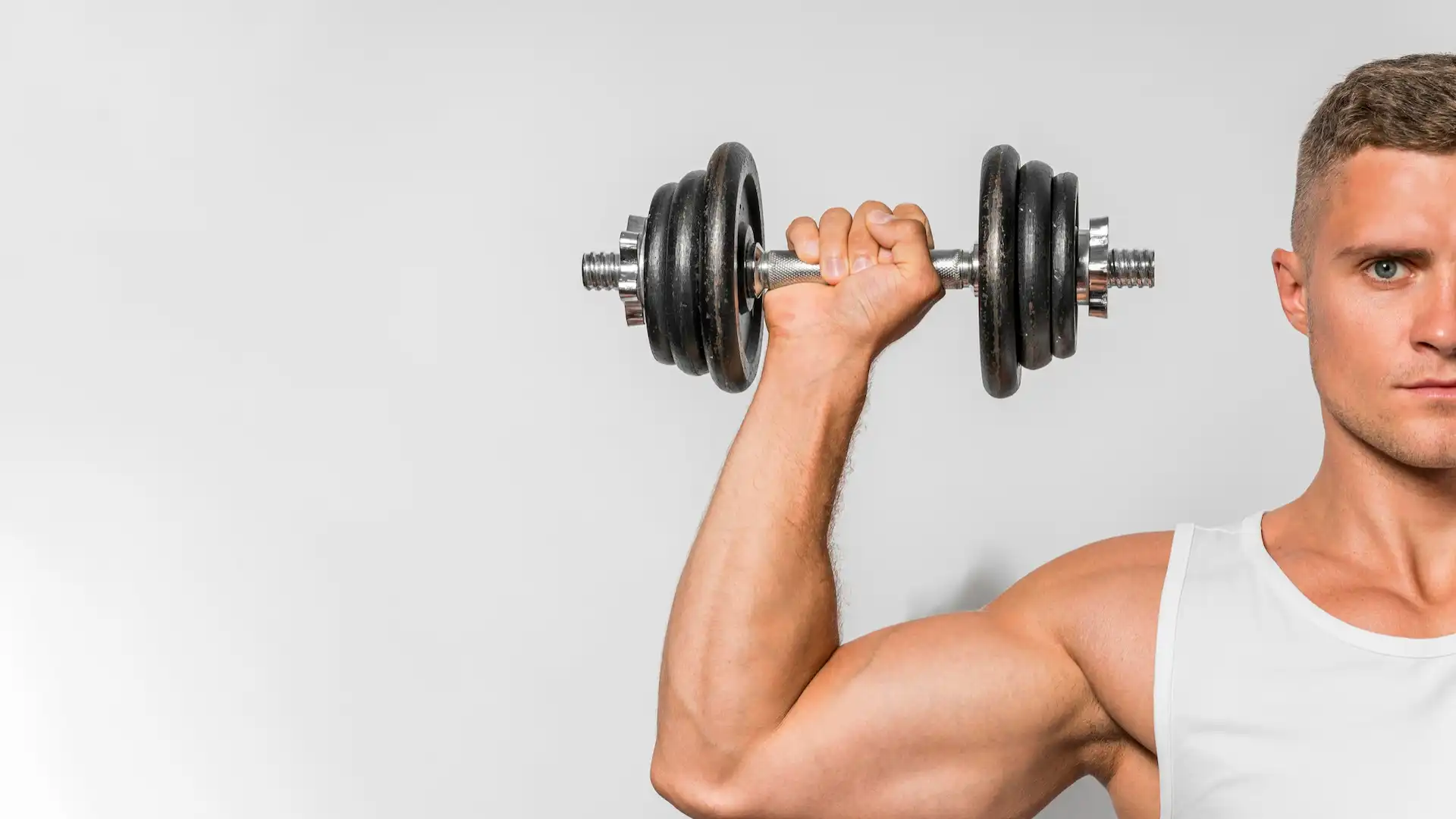 Homem segurando um haltere, equipamento básico para fazer musculação em casa.