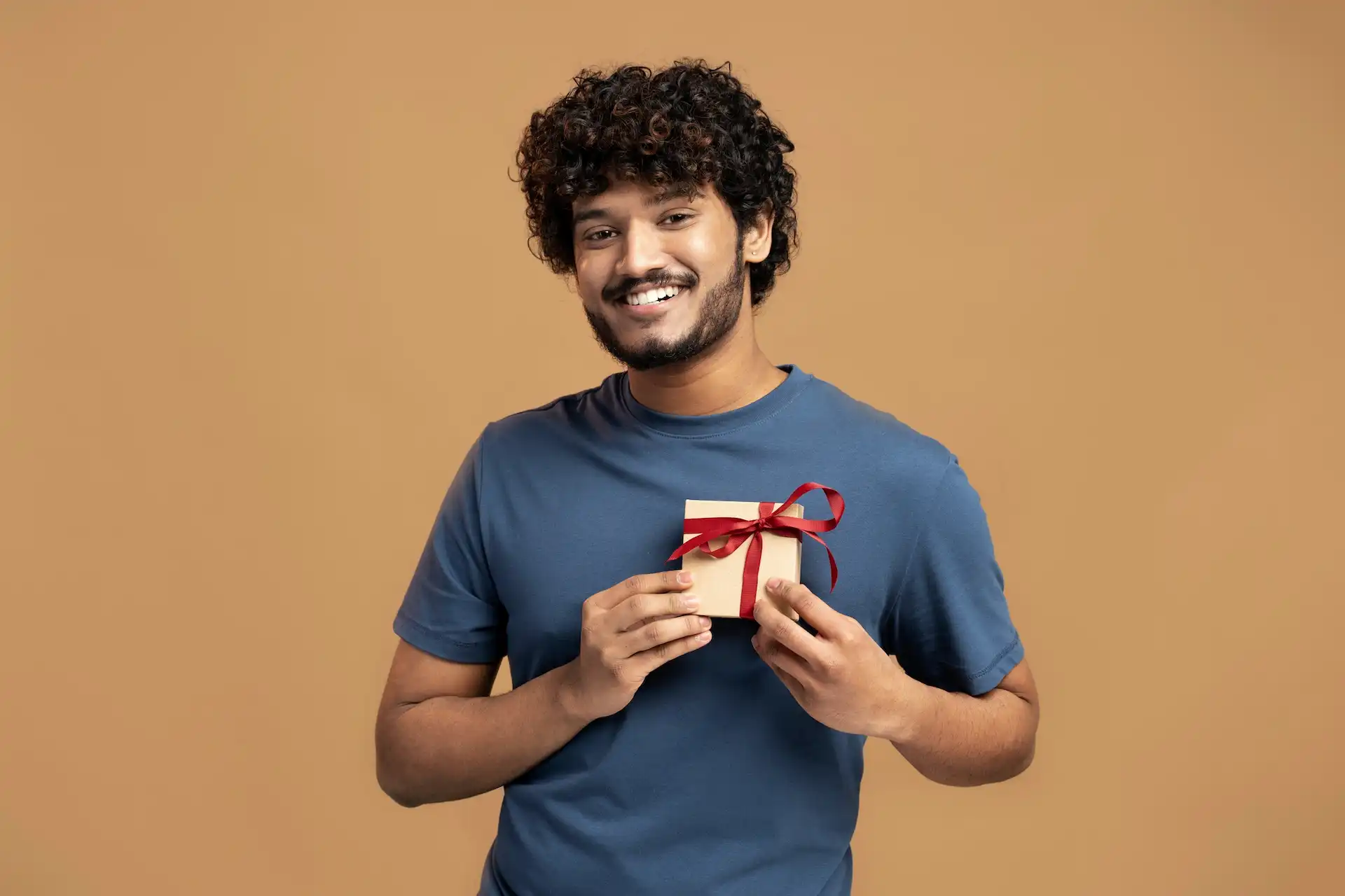 Homem sorridente segurando uma caixa de presente.