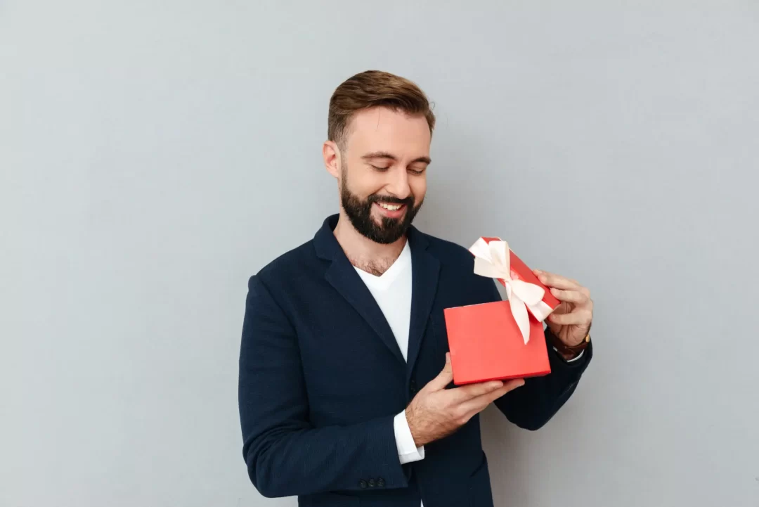 Homem sorridente abrindo uma caixa de presente