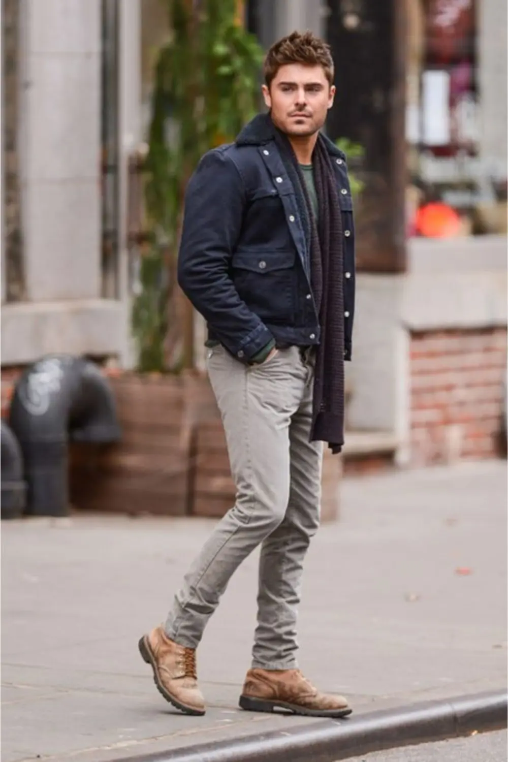 Homem utilizando bota, calça, camisa, jaqueta e cachecol.