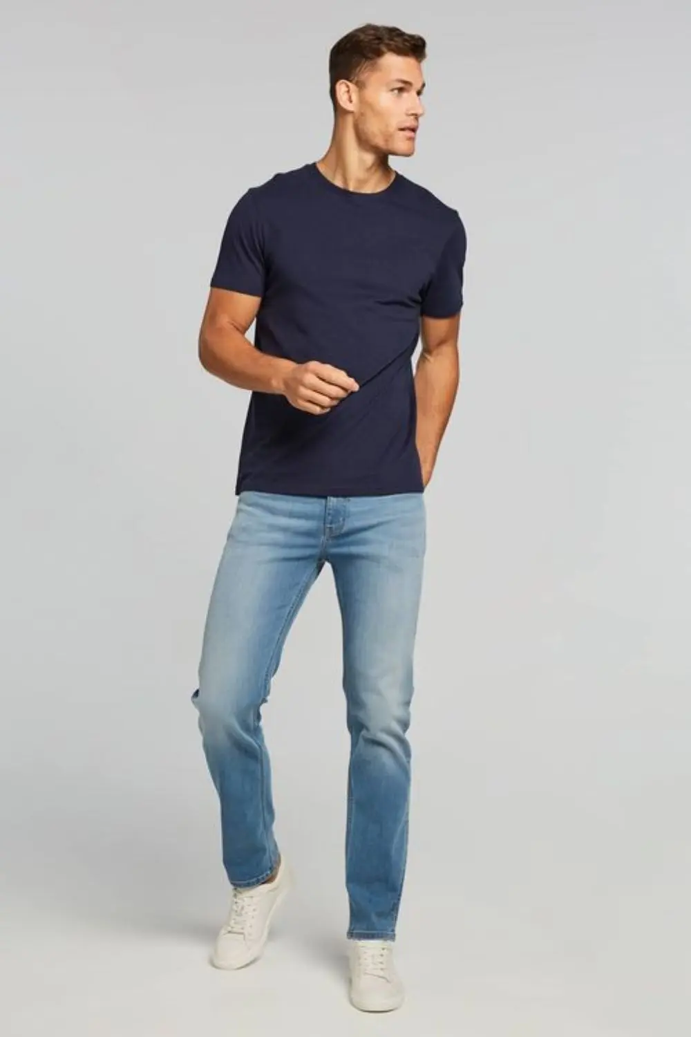 Homem utilizando calça jeans, camiseta básica e tênis. Um clássico look casual básico.