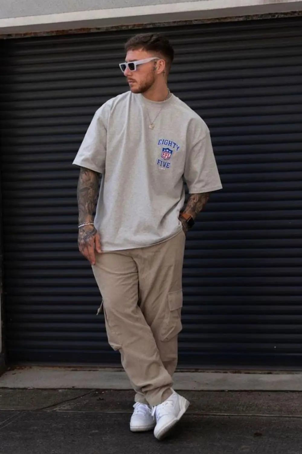 Homem utilizando tênis, calça e camiseta larga, e óculos escuros. Um exemplo de streetwear, um dos tipos de estilos masculinos mais populares.