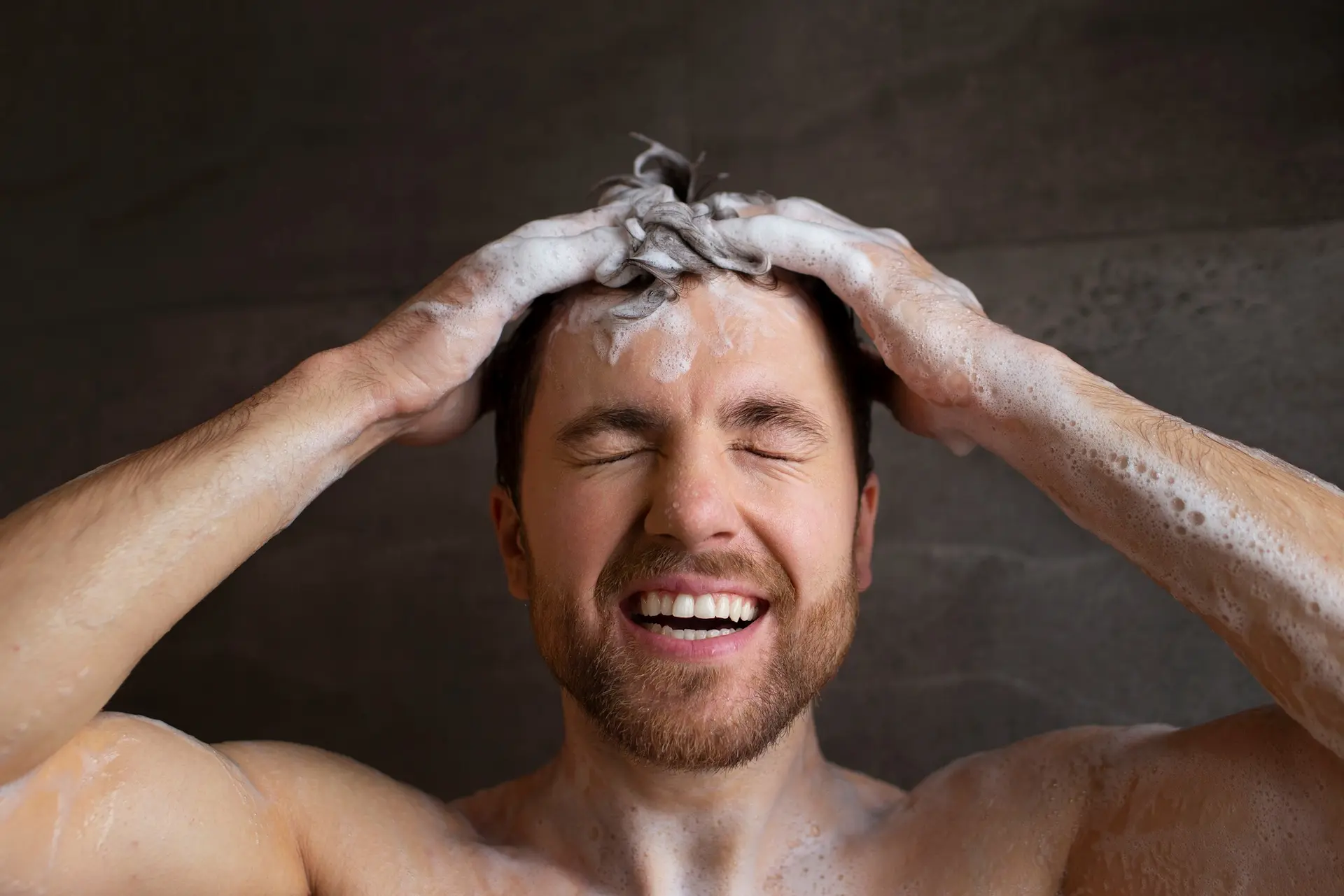 Homem lavando o cabelo com shampoo masculino.