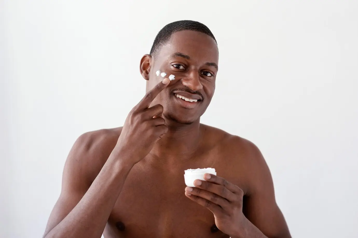 Homem passando hidratante no rosto em uma rotina de cuidados masculinos.