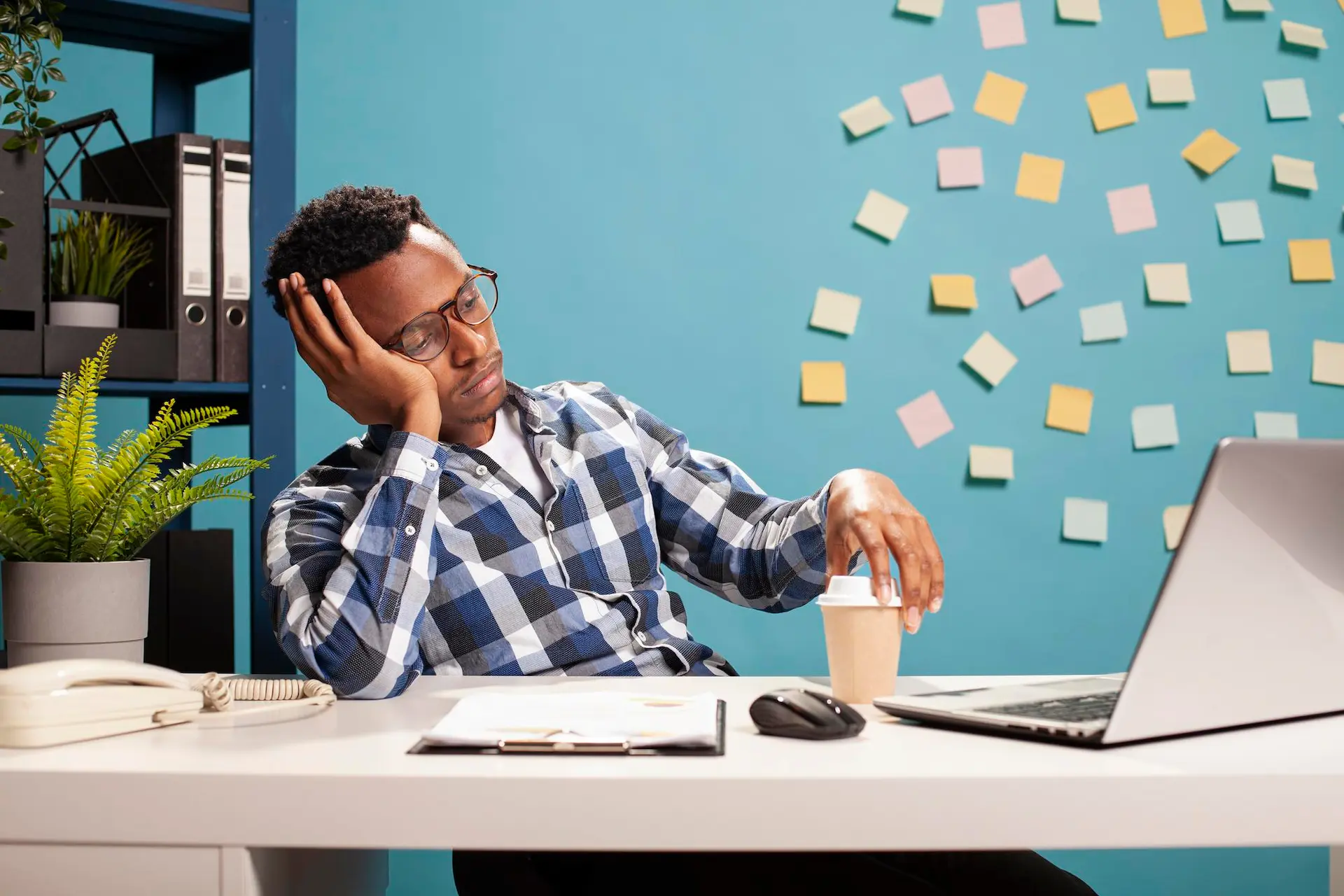 Homem entendiado sentado em frente a um notebook.
