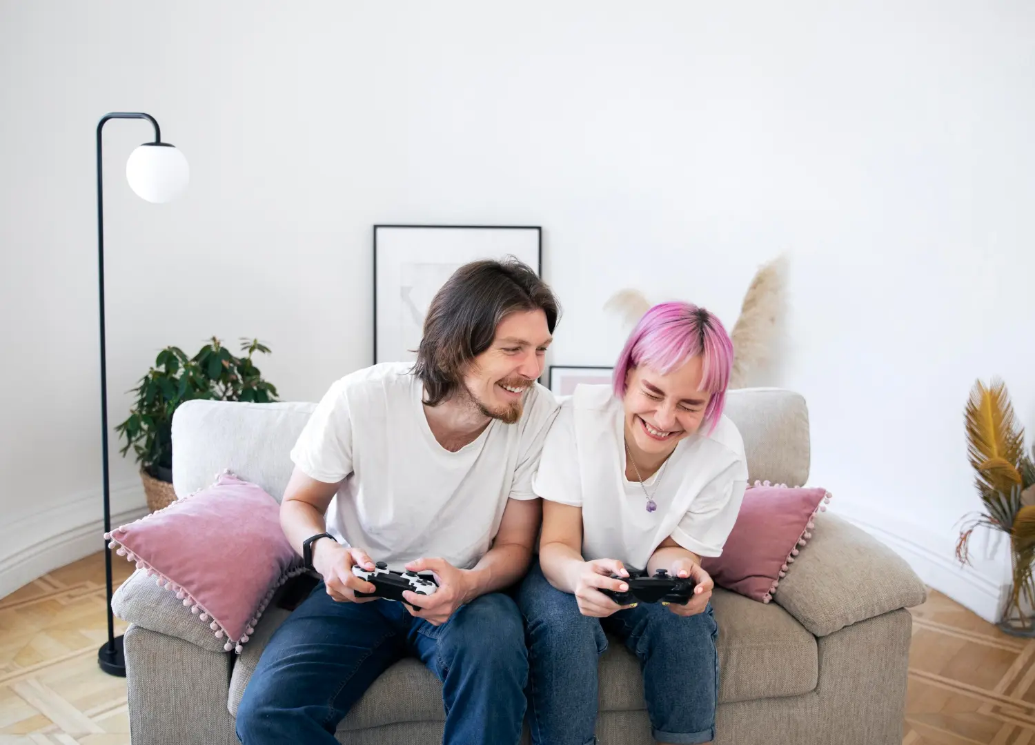 Homem e mulher jogando videogame, sentados no sofá.
